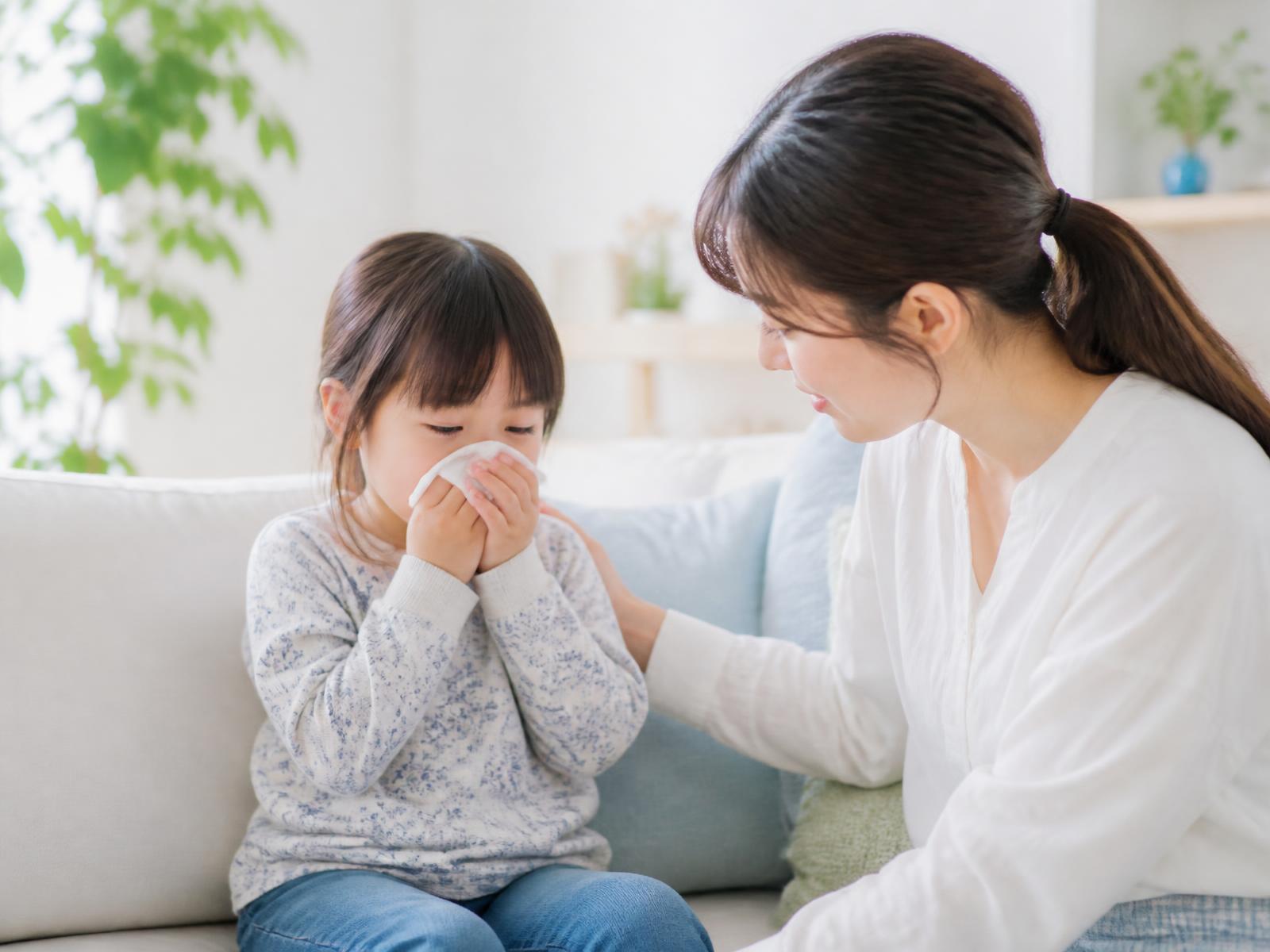 鼻をかむ子どもと、その様子を気にかける母親